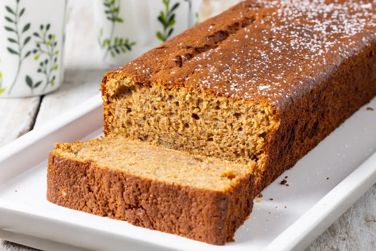 Fetta di banana bread light, soffice e dorata, cosparsa di zucchero a velo. Perfetta per una colazione leggera.