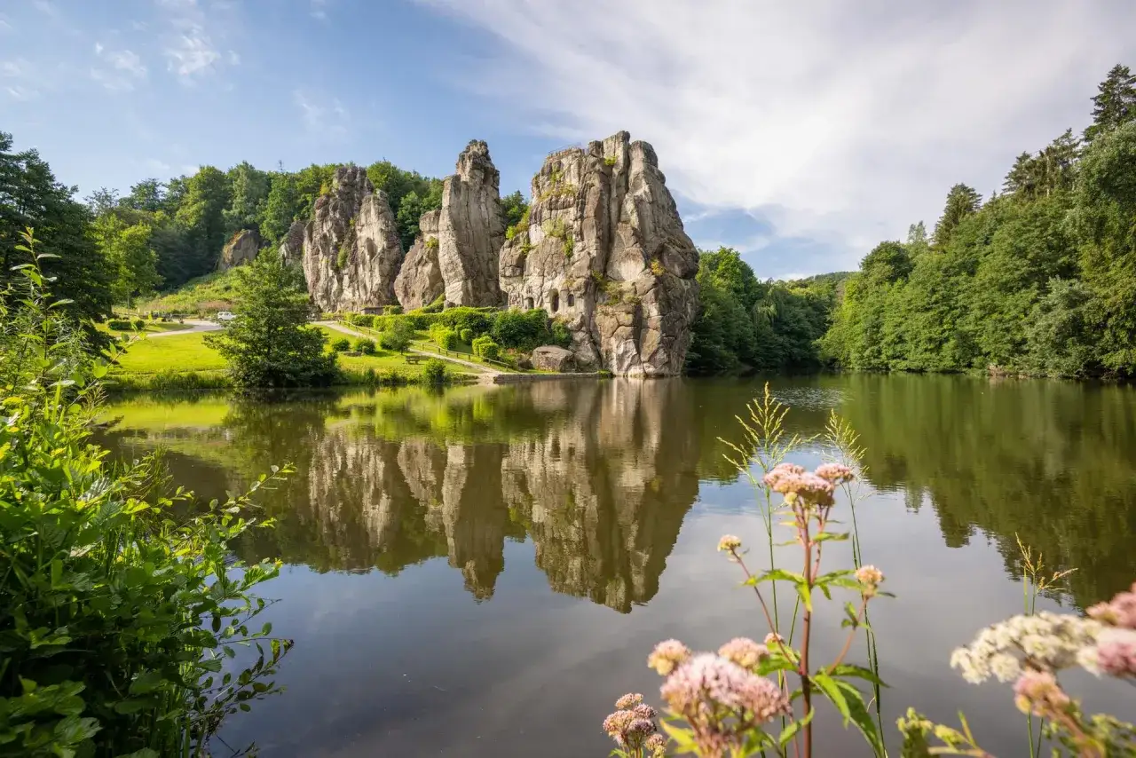 Die Externsteine NRW, eine beeindruckende Felsformation, spiegeln sich im ruhigen Wasser eines Sees.