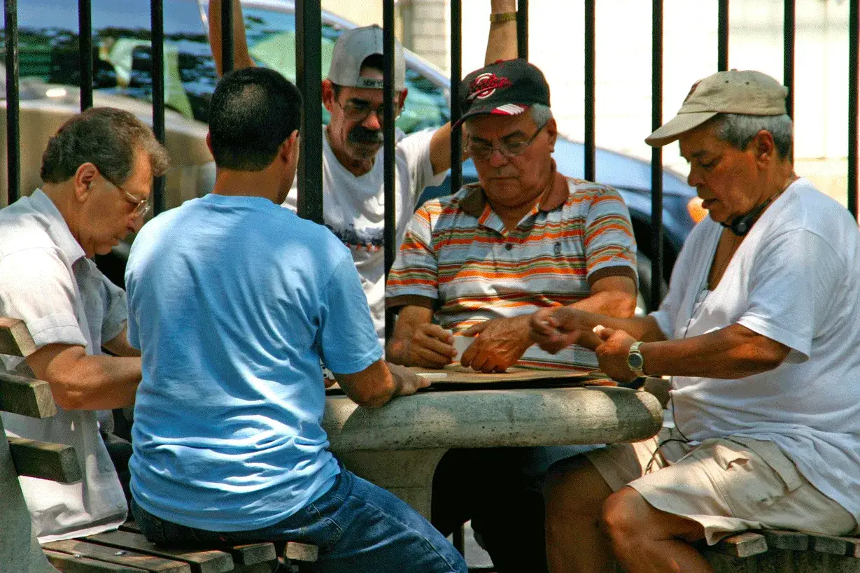 Cinq hommes discutent autour d'une table en pierre. Une leçon sur comment se faire des nouveaux amis : partager un moment simple.