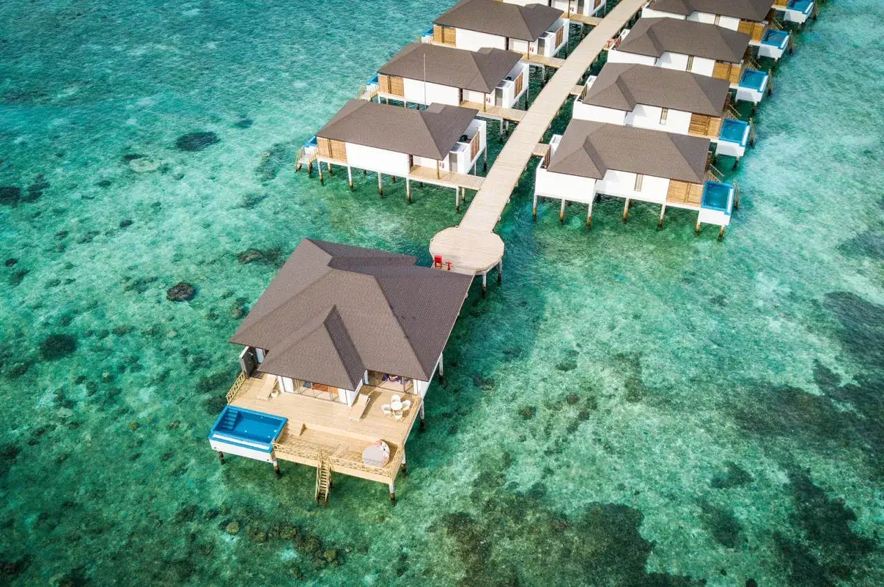 Traumhafte Wasservillen mit privaten Pools, wie im Robinson Noonu, ragen aus dem türkisfarbenen Meer.