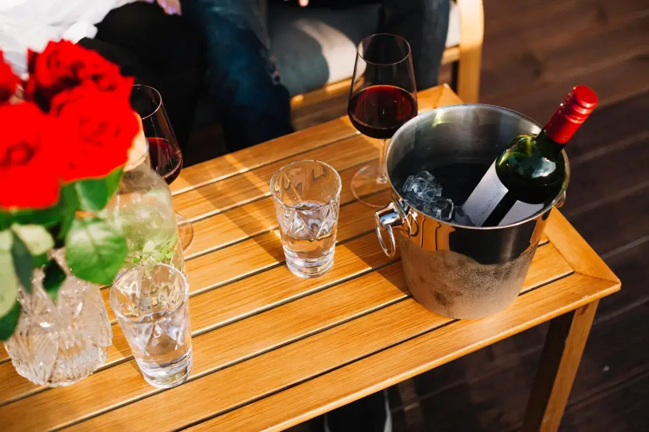 Seau à glace pour garder le vin au frais à table, avec des verres et des roses rouges.