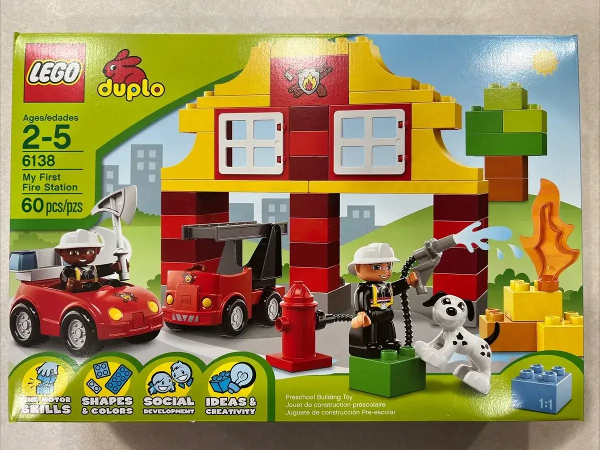 LEGO DUPLO Feuerwehr Anleitung: Ein Feuerwehrmann l&ouml;scht mit einem Schlauch einen brennenden Baum. Ein Hund schaut zu.
