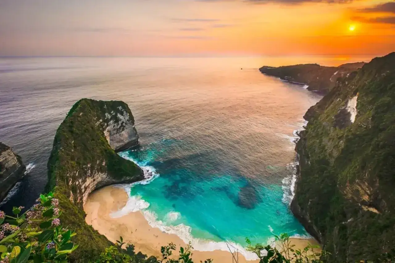 Spektakularne plaze Bali o zachodzie słońca. Turkusowa woda, piaszczysta plaża i zielone klify tworzą rajski widok.