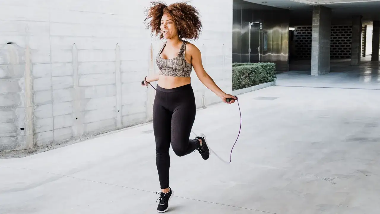 Femme souriante faisant de la corde à sauter, un excellent exercice pour renforcer le périnée.