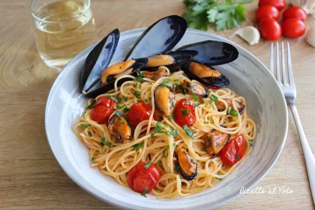 Spaghetti con le cozze e pomodorini, un piatto di mare profumato e colorato, pronto per essere gustato con un bicchiere di vino bianco.