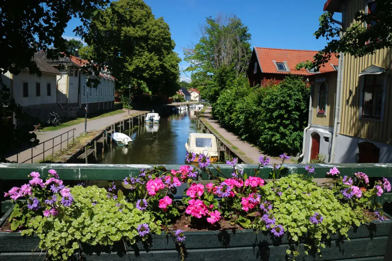 En vacker kanal med båtar, hus och blommor. Perfekt för en bilsemester i Sverige.