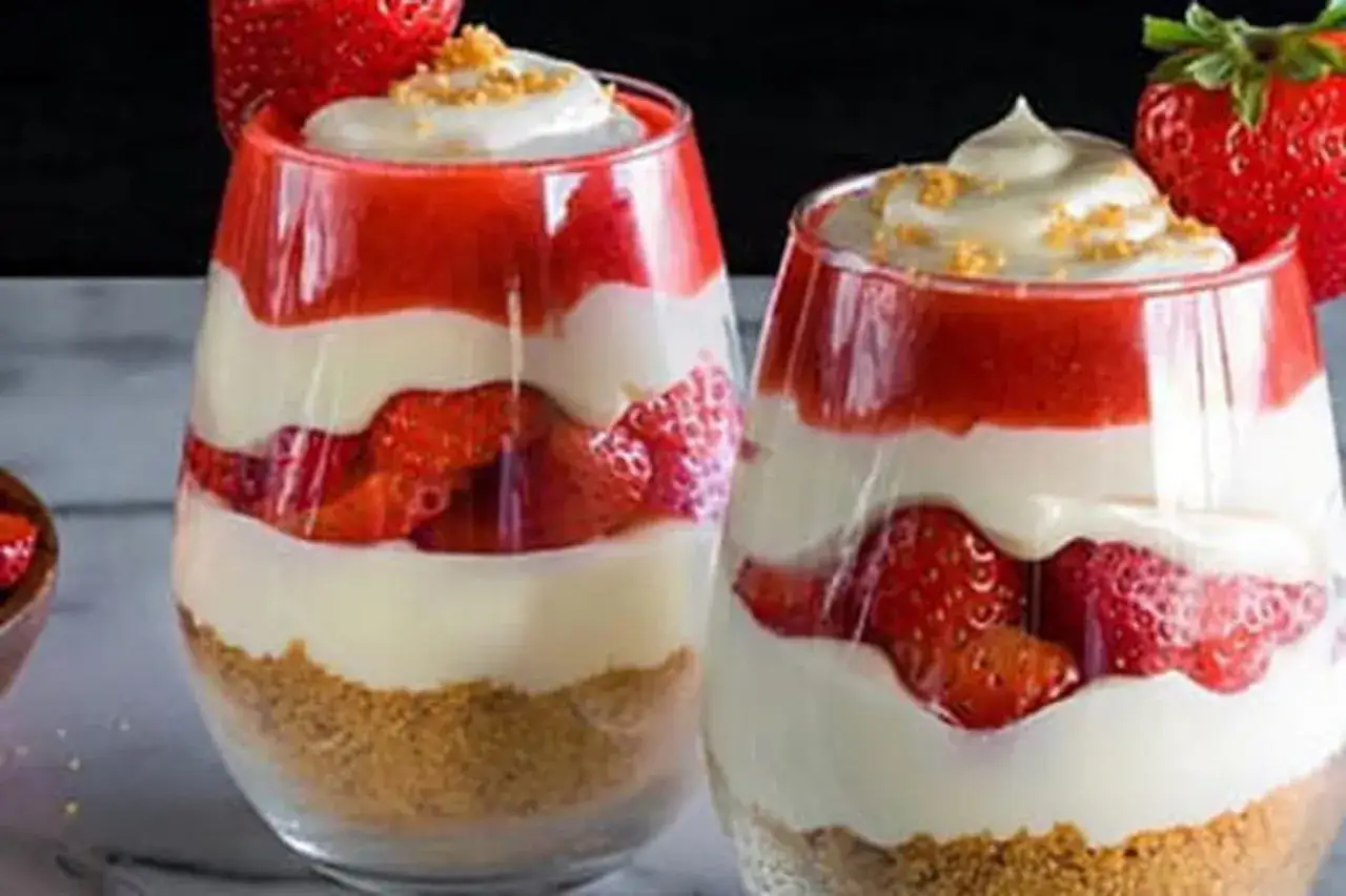 Deux verrines de dessert fraise, superposant biscuits &eacute;miett&eacute;s, cr&egrave;me onctueuse et morceaux de fraises fra&icirc;ches, le tout garni d'une touche de cr&egrave;me et de miettes.