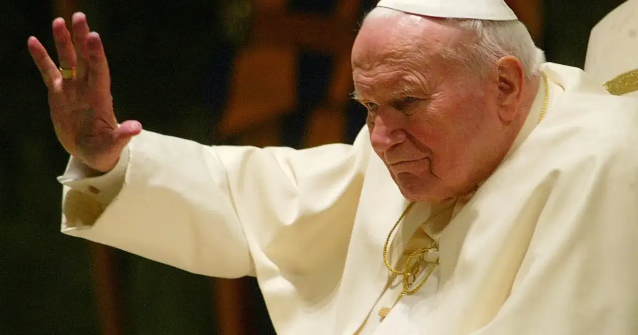 Papież Jan Paweł II w białej szacie, z podniesioną dłonią, symbolizujący modlitwę do Jana Pawła II o uzdrowienie z raka.