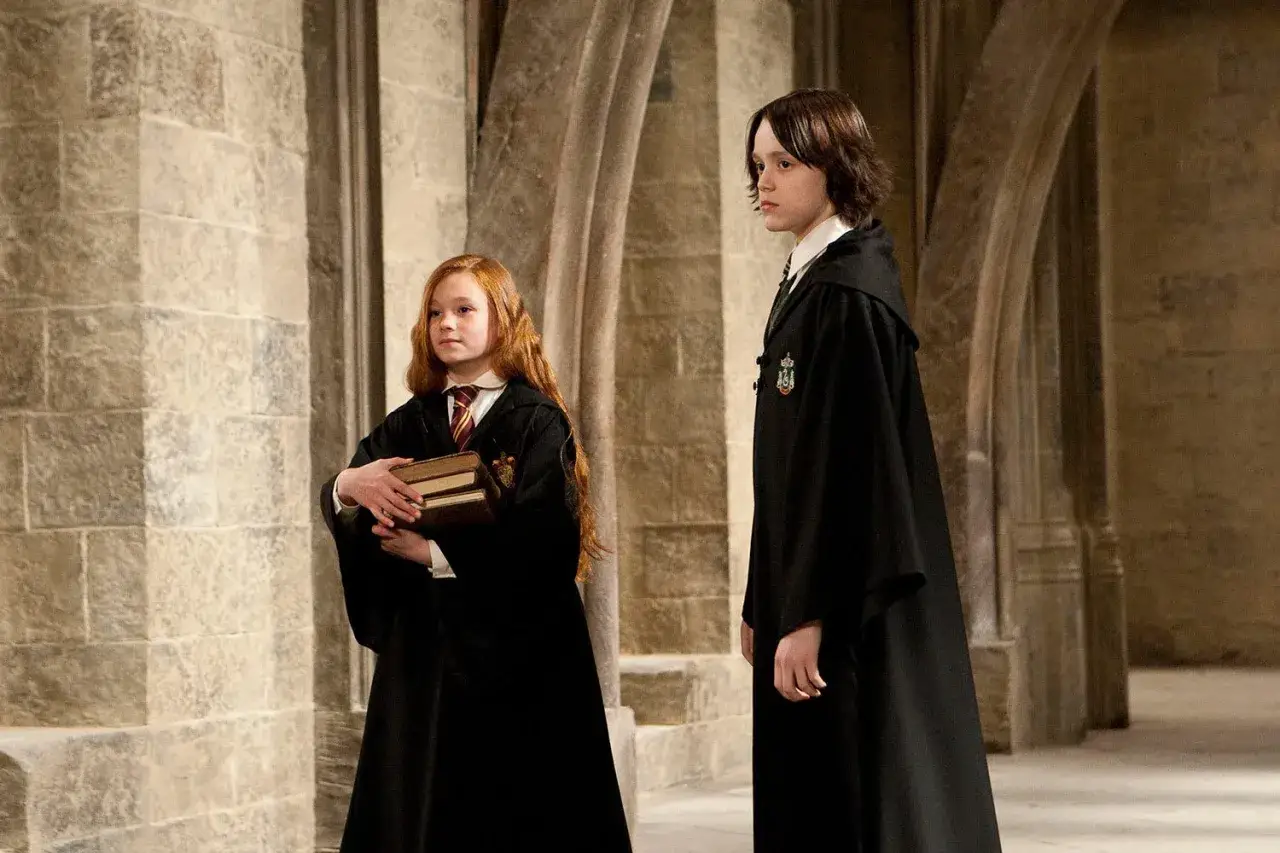 Młody Severus Snape w szacie Slytherinu, obok rudowłosej uczennicy z książkami.