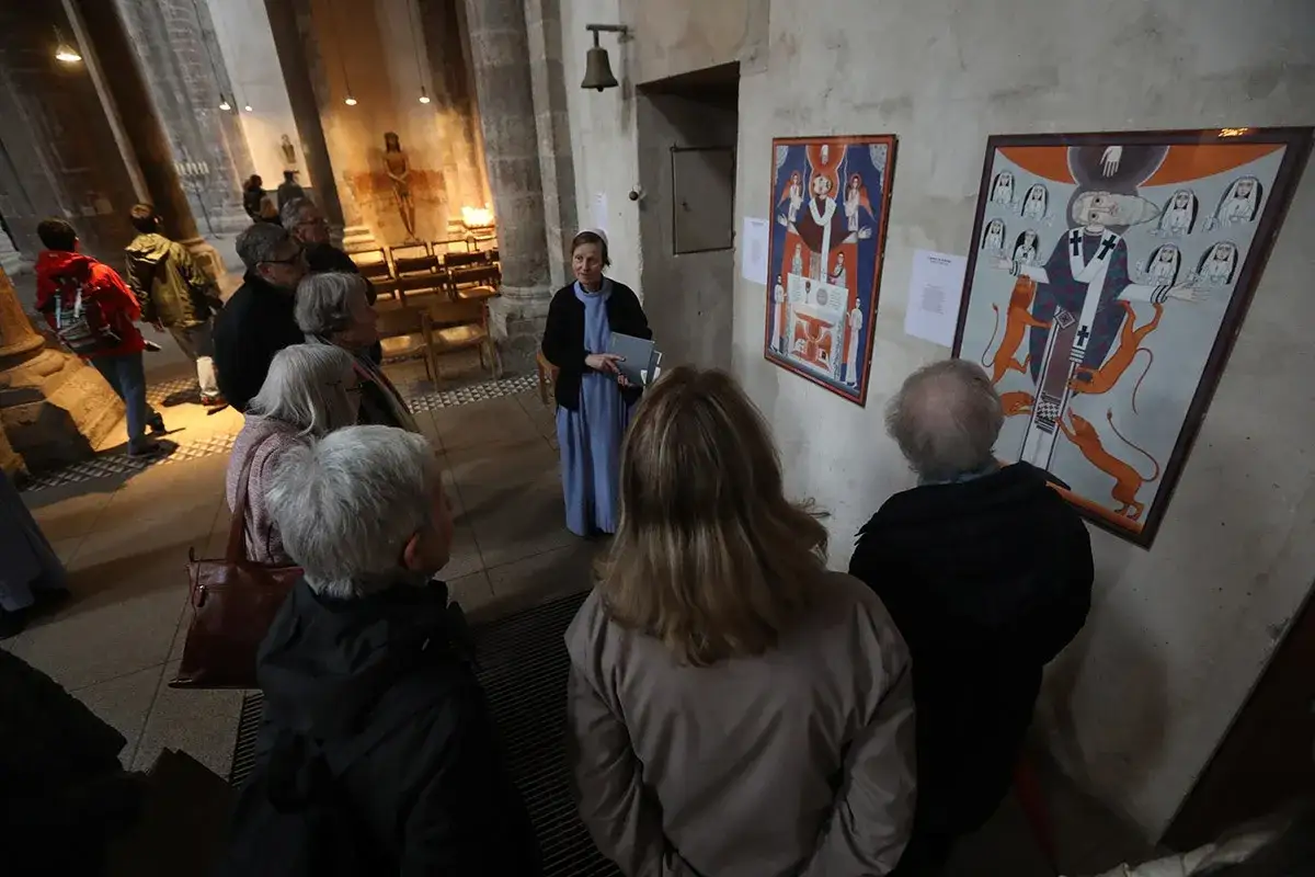 Besucher betrachten Kunstwerke in einer Kirche, die m&ouml;glicherweise die Gemeinschaft von Jerusalem und Kritik thematisieren.