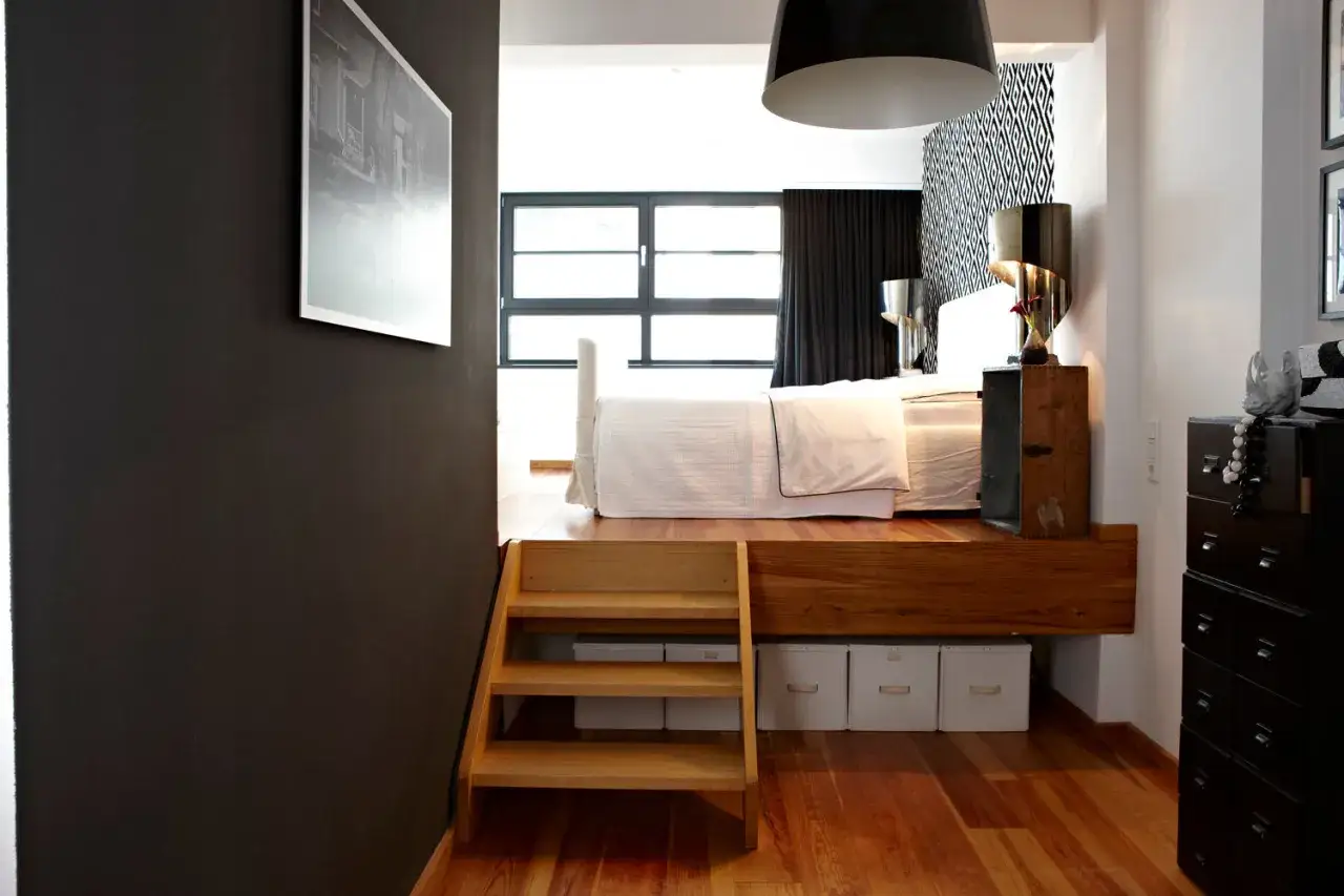 Eine moderne Schlafnische gestalten: Holzpodest mit Bett, Stauraum darunter und eine kleine Holztreppe.