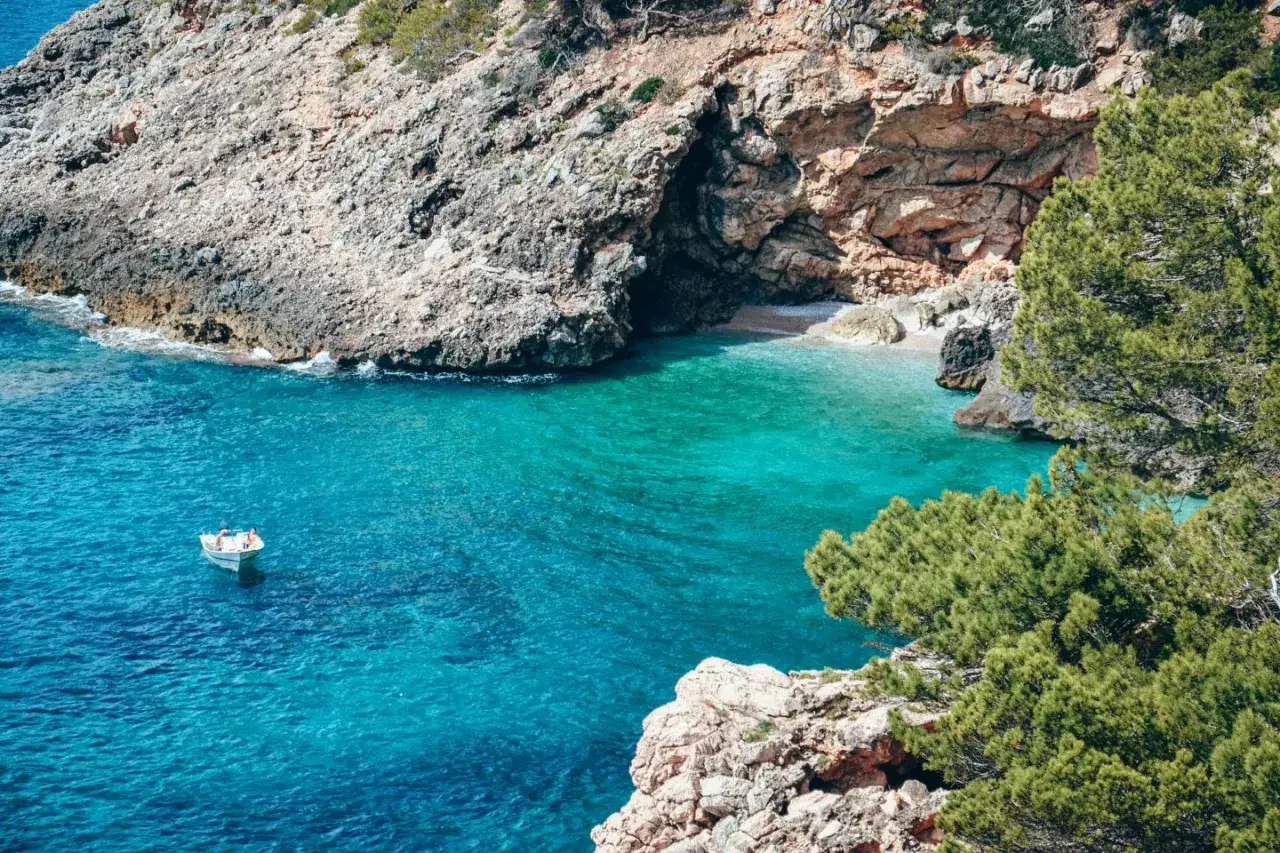 Turkusowa zatoczka na największej wyspie Balearów. Mała łódka kołysze się na falach.