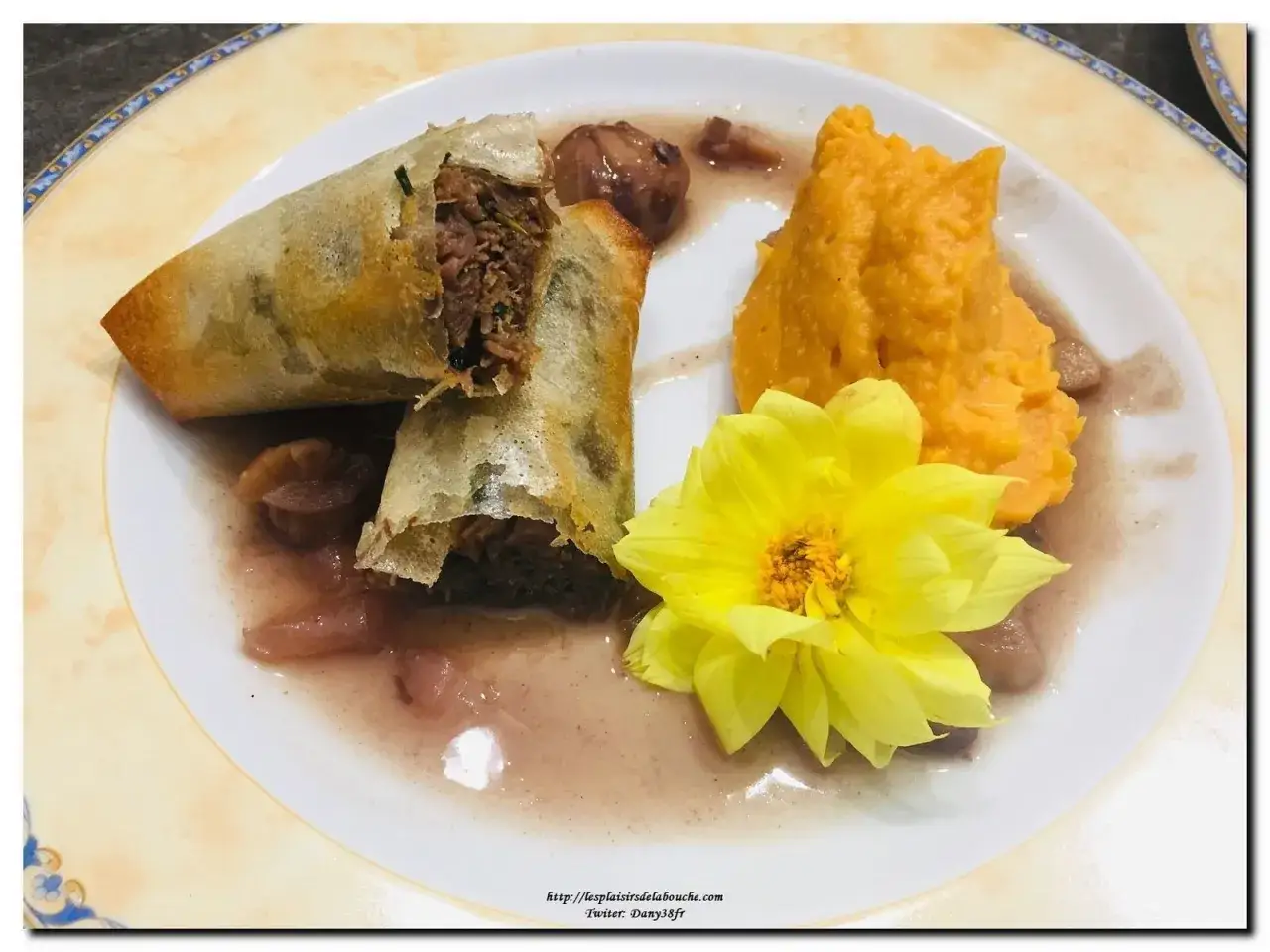 Deux rouleaux croustillants d'effiloch&eacute; de canard en feuille de brick, servis avec une pur&eacute;e orang&eacute;e et une fleur jaune.