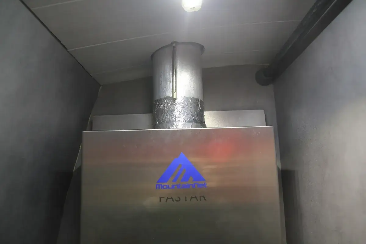 Détail d'une cheminée chauffe eau en inox, avec un conduit d'évacuation gainé de papier aluminium.