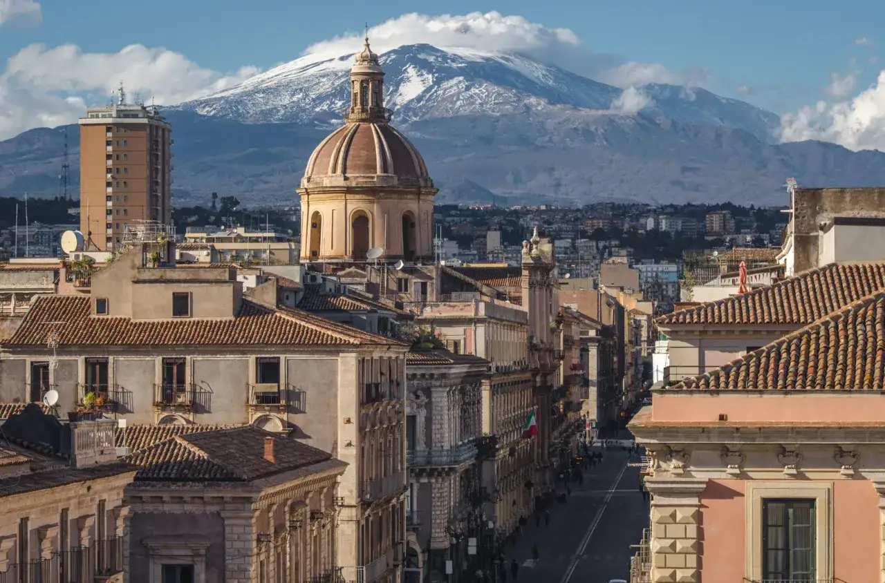 Widok na Katanię z dominującą kopułą i ośnieżonym Etna w tle. Miasto tętni życiem, a pytanie