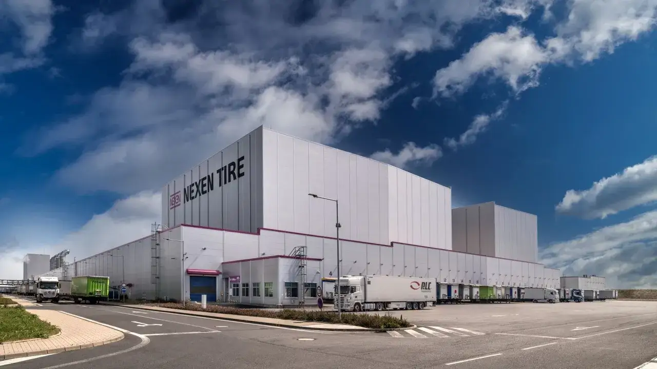 Nowoczesny magazyn Nexen Tire, producenta opon, z zaparkowanymi ciężarówkami pod dokami załadunkowymi.