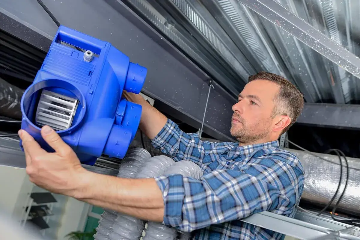 Un technicien installe un nouveau bloc VMC. L'entretien vmc obligatoire garantit un air sain.