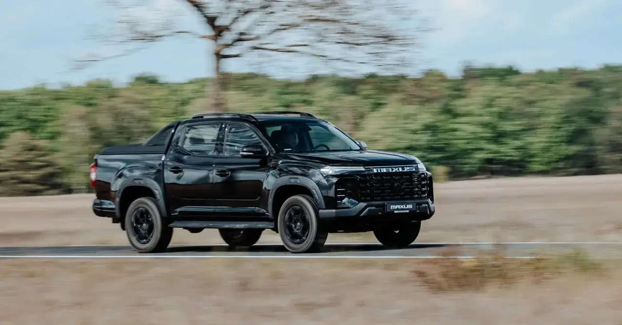 Czarny Maxus pickup pędzi po drodze, otoczony rozmazanym krajobrazem z drzewami w tle.