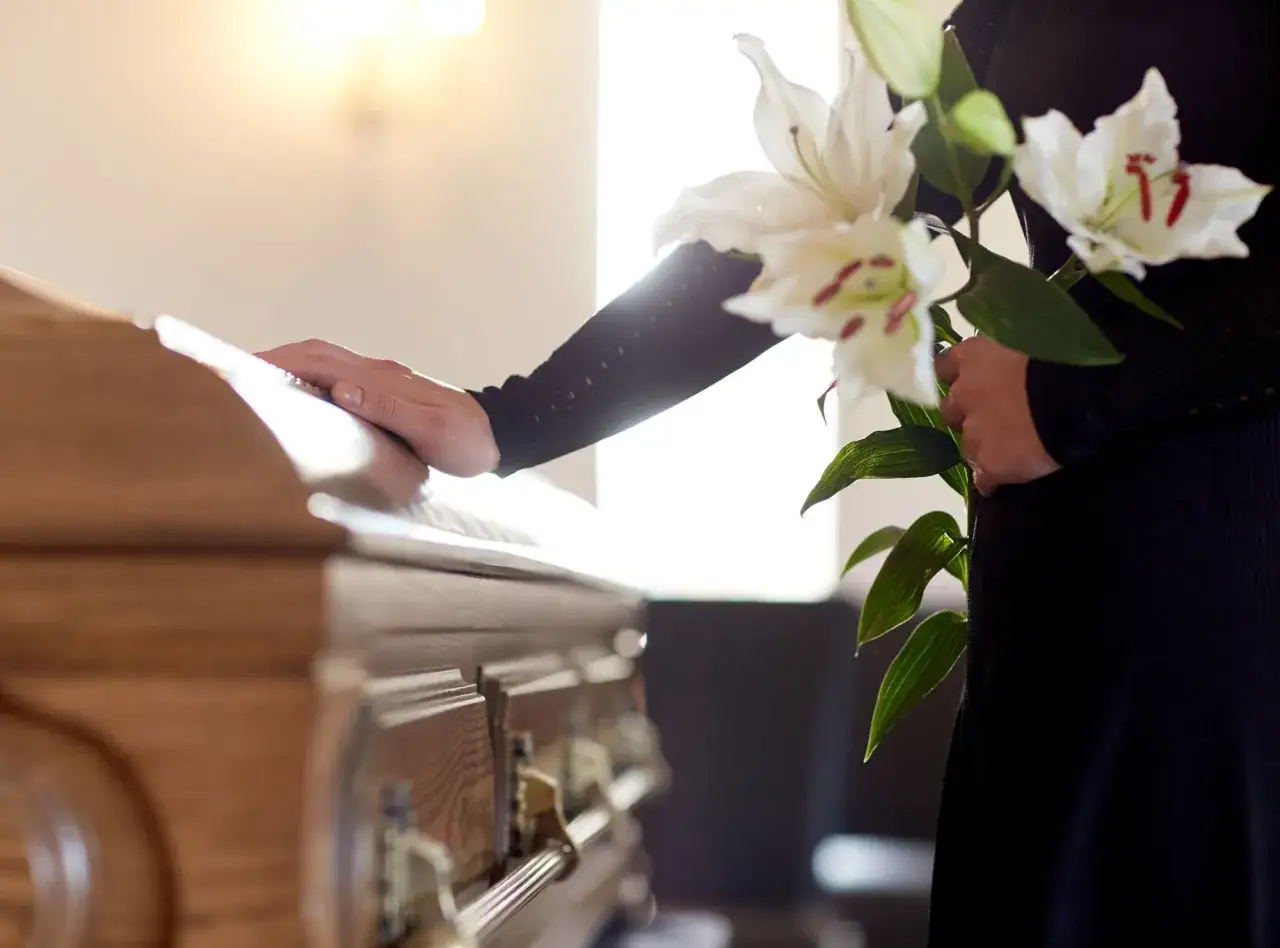 Trauer um den tod der schwiegermutter. Eine Hand ruht auf dem Sarg, Blumen in der anderen.