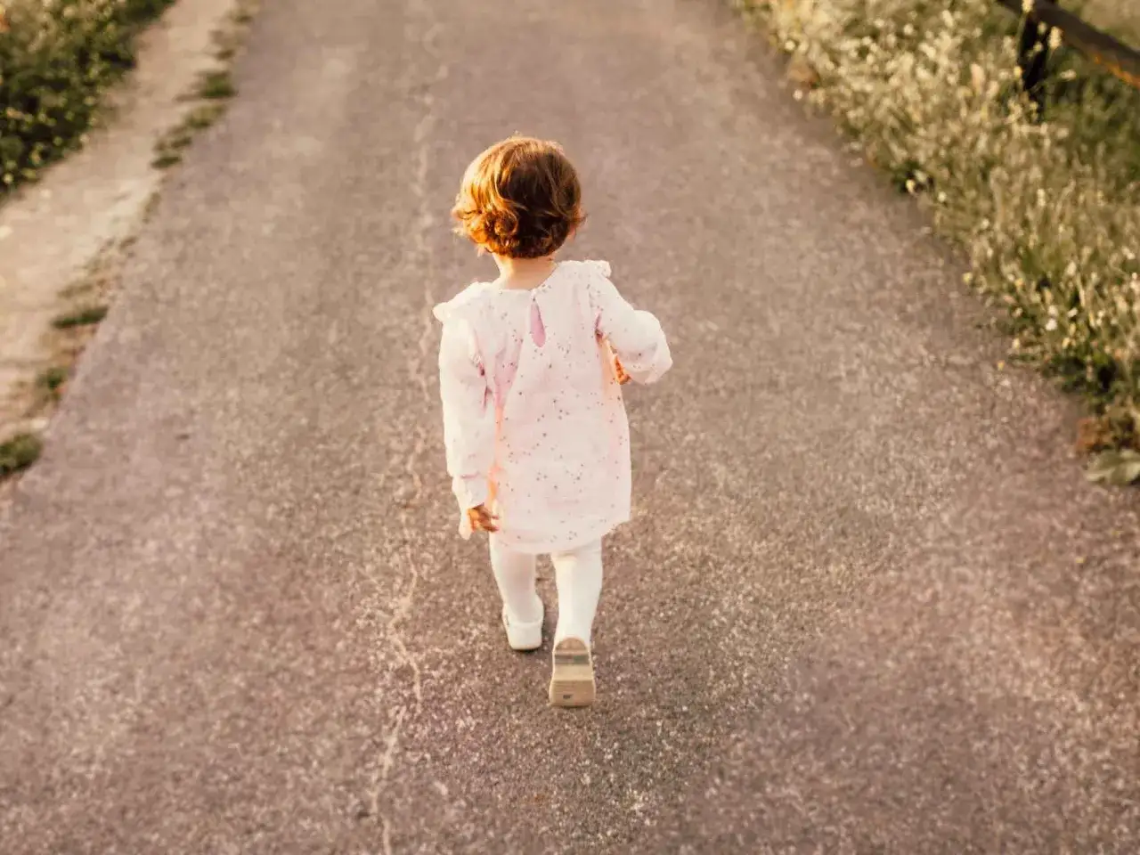 Niña con vestido rosa camina por un sendero. Su nombre, Arlet, evoca la pureza y la inocencia de este momento.
