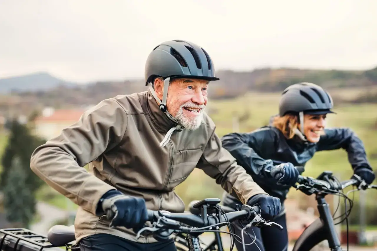 Gl&uuml;ckliches &auml;lteres Paar testet e-Bikes auf einer Fahrt durch die Natur.