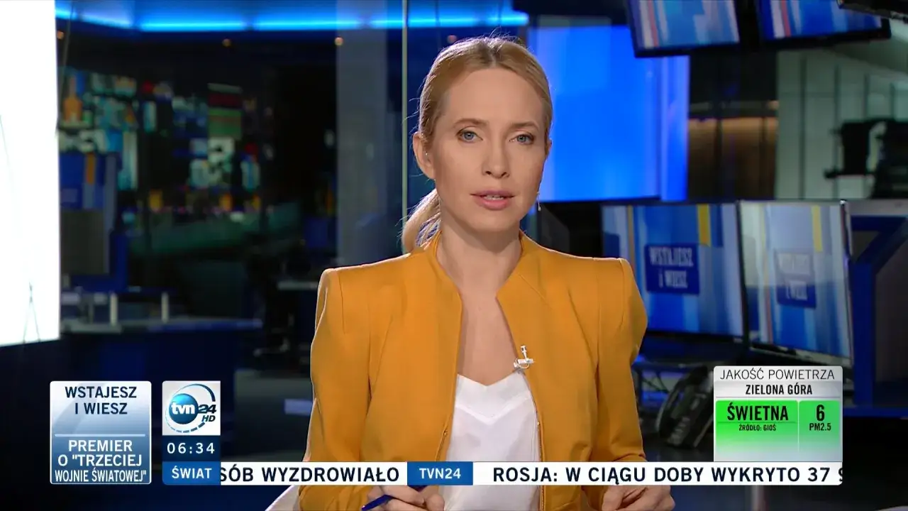 Monika Tomasik, dziennikarka TVN24, w żółtej marynarce informuje o premierze i wojnie światowej.