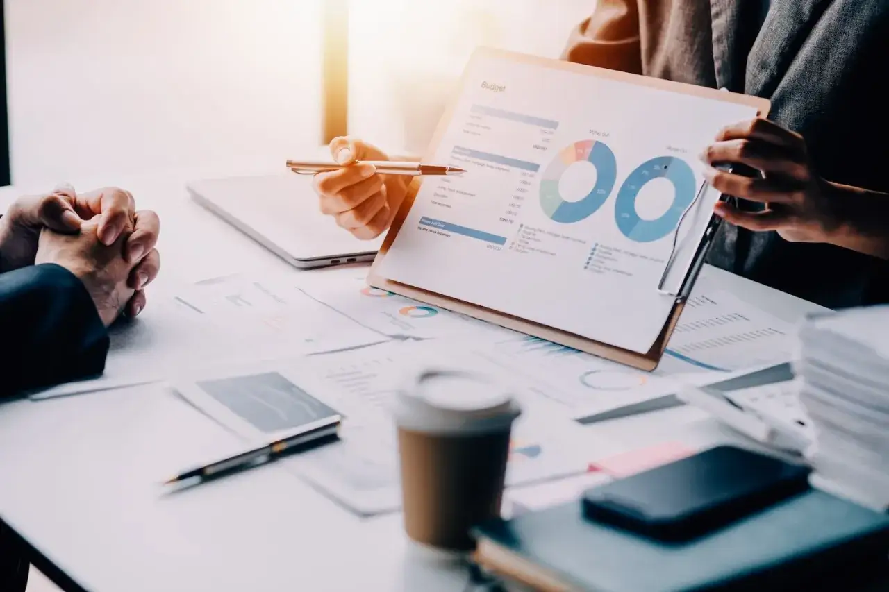 Una gestora de fondos analiza un presupuesto con gráficos circulares y datos financieros.
