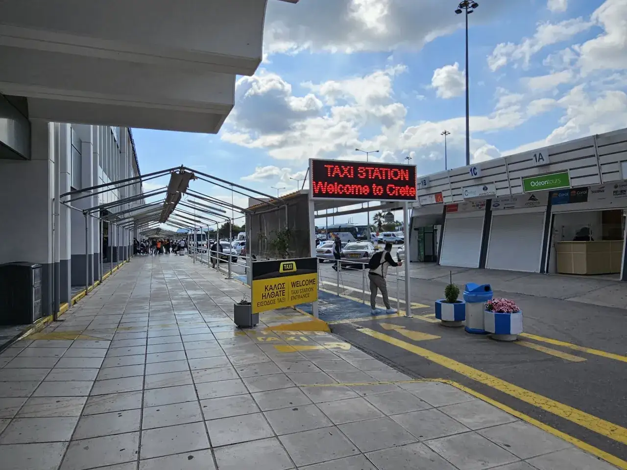 Vid Heraklion flygplats möts resenärer av en stor skylt som önskar dem välkomna till Kreta. Taxistationen är tydligt markerad.