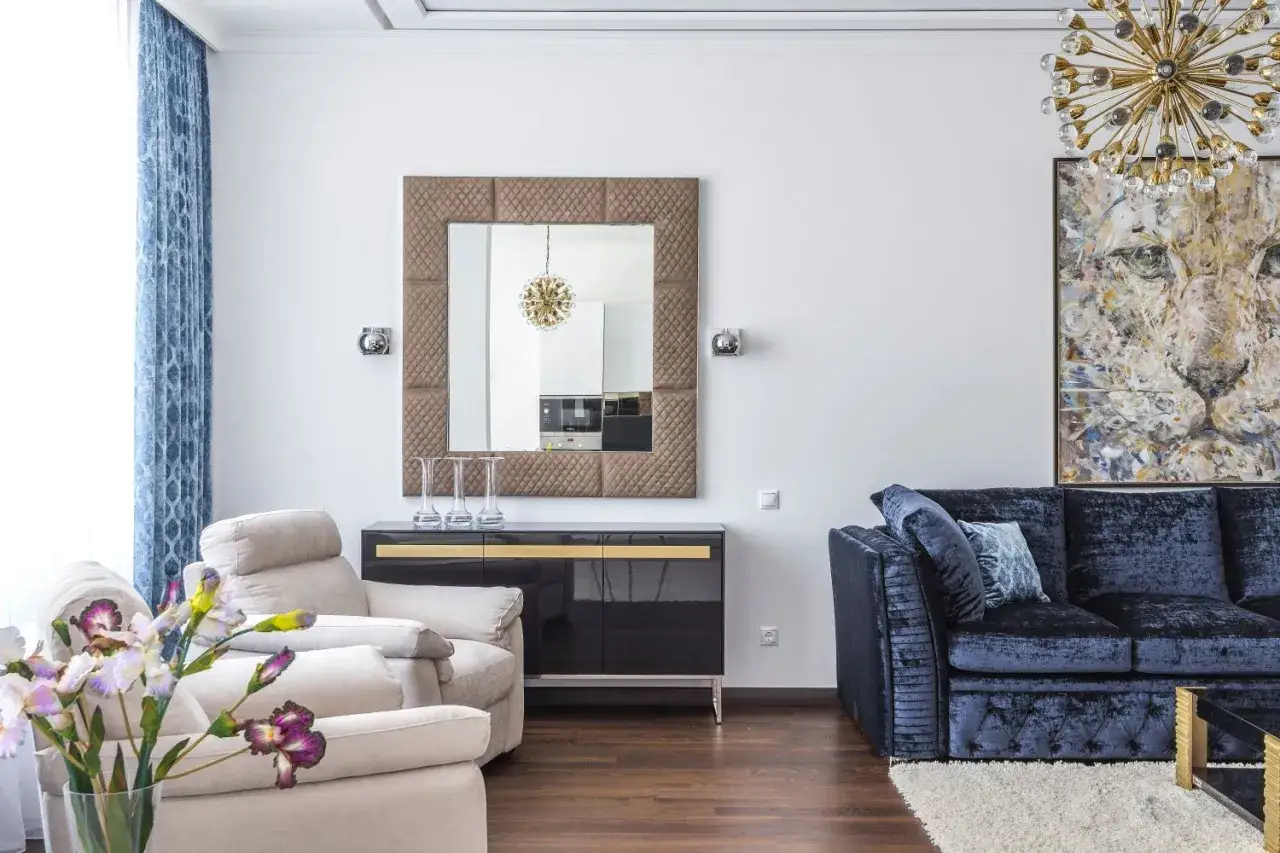 Elegancki salon z granatową kanapą i obrazem lwa. Lustro nad komodą to świetny sposób, by pokazać, na czym powiesić obraz bez wiercenia.