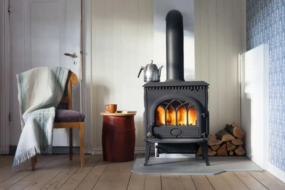 Poêle à bois crépitant, offrant un chauffage naturel et une ambiance chaleureuse. Une couverture douillette sur une chaise invite à la détente.