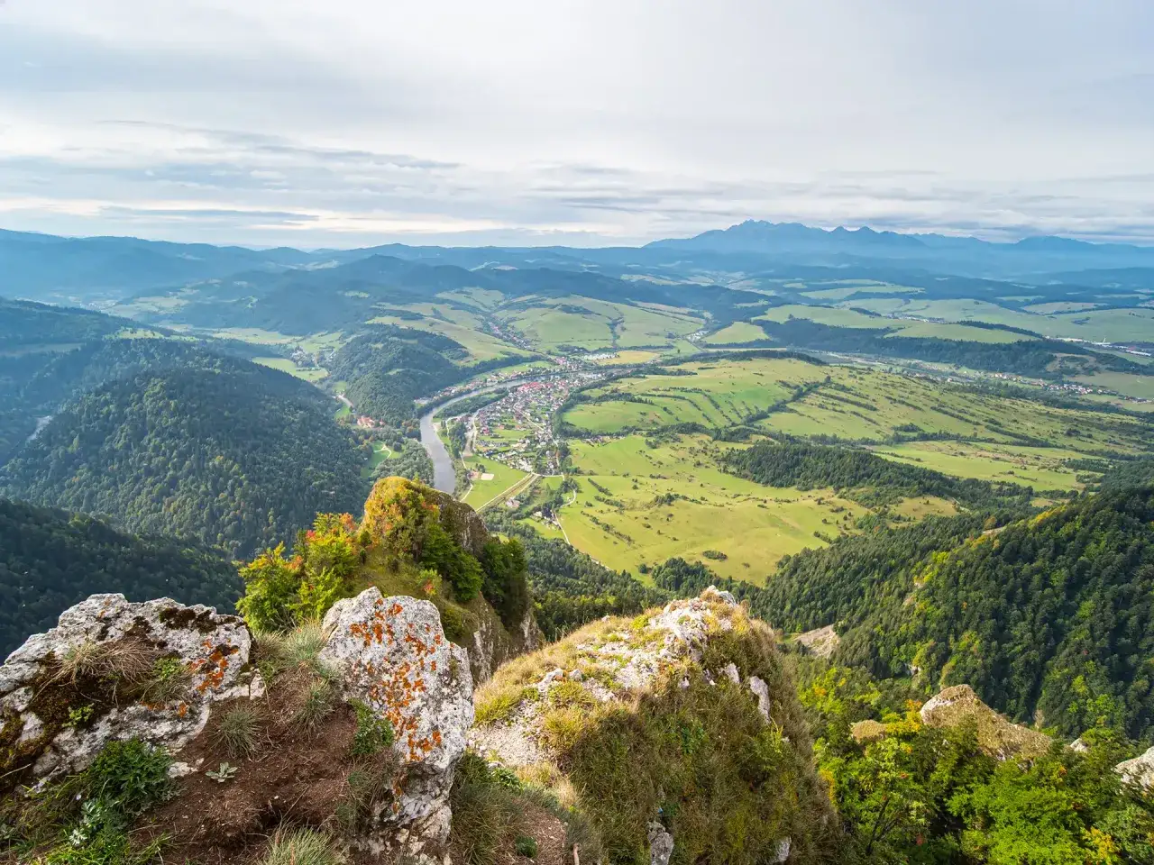 Widok z Trzech Koron na dolinę Dunajca i Tatry. Nazwy szczytów w oddali giną w mgiełce.