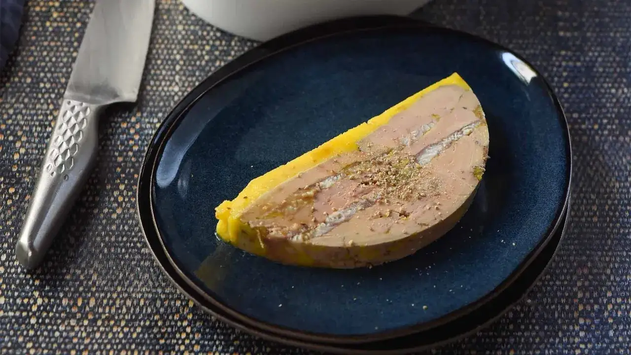 Tranche de foie gras, un mets délicat, sur une assiette bleue. Ce plat, souvent servi en entrée, est une spécialité française.