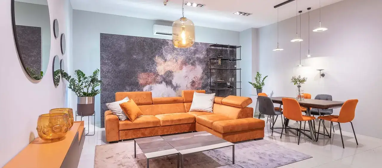 Nowoczesny salon z narożnikiem w intensywnym pomarańczowym kolorze, stolikami kawowymi i jadalnią.