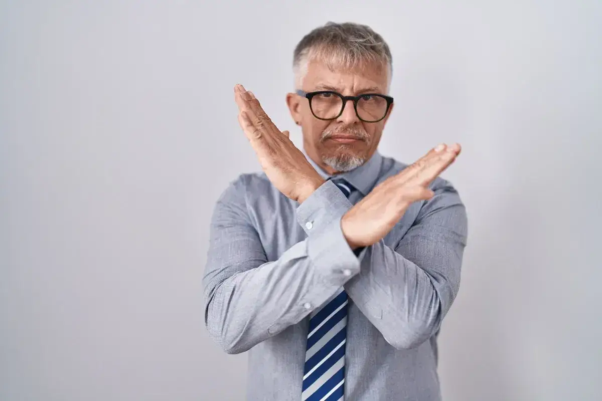 Mężczyzna w okularach z rękami skrzyżowanymi na piersi, gestem 