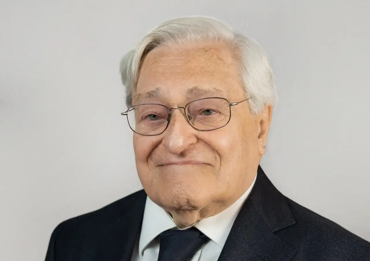Un uomo anziano con occhiali e abito scuro, un esempio di chi ha deciso di diventare avvocato a 50 anni, dimostrando che non è mai troppo tardi per realizzare i propri sogni.