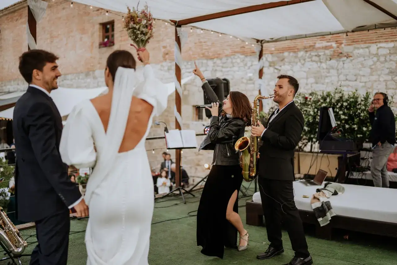 Novios bailan al ritmo de las **canciones de boda** interpretadas por una banda en vivo, con una cantante y un saxofonista.