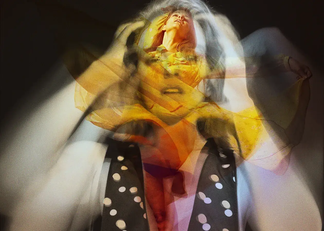 Un volto femminile emerge da un vortice di giallo e bianco, un'istantanea di movimento catturata in un tempo di scatto fotografia.
