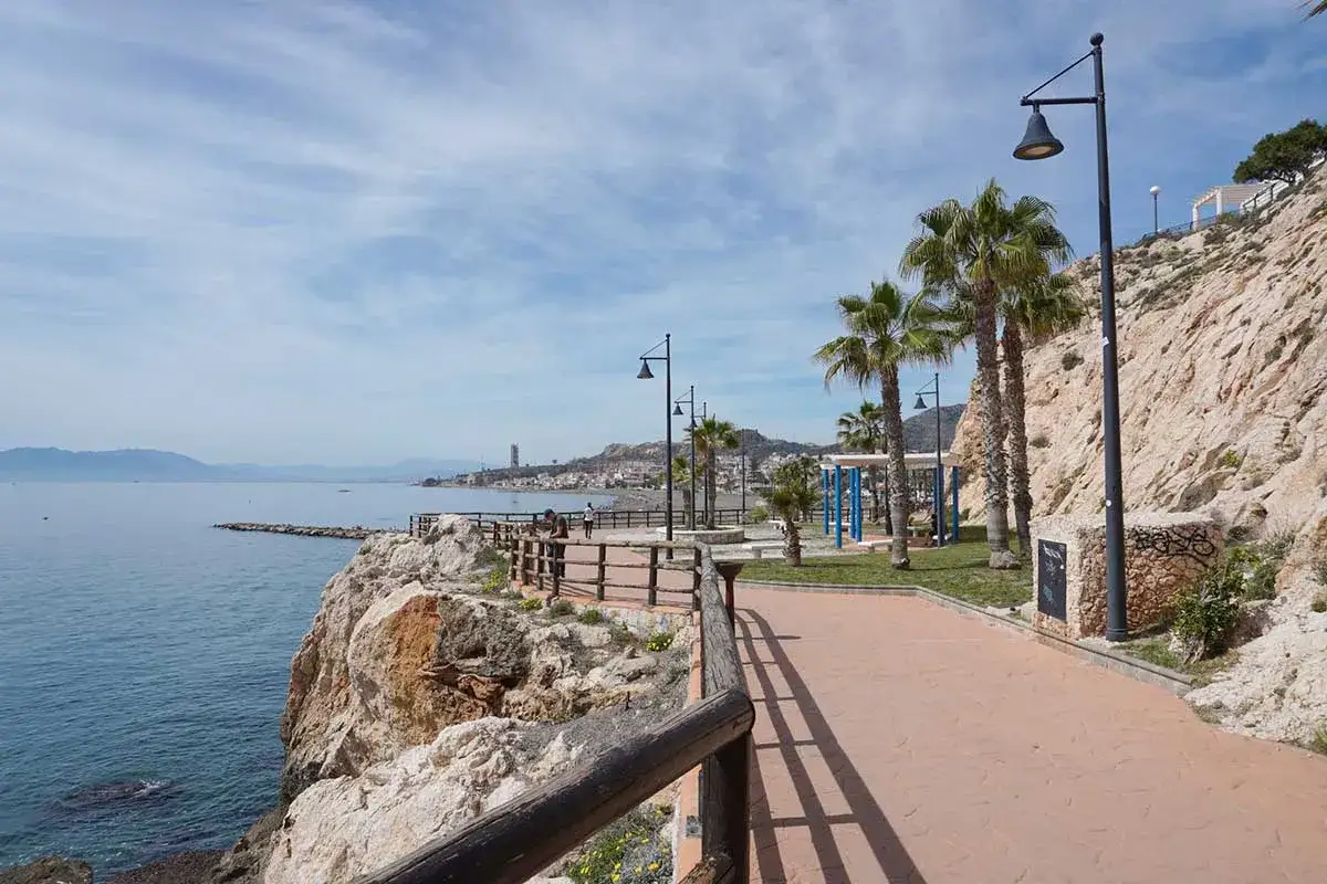 Promenade am Meer in Rinc&oacute;n de la Victoria mit Palmen, Felsen und Blick auf die K&uuml;stenstadt.