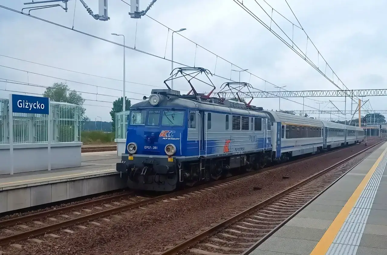 Pociągi na Mazury czekają na pasażerów na stacji Giżycko. Niebiesko-szara lokomotywa PKP Intercity gotowa do podróży.