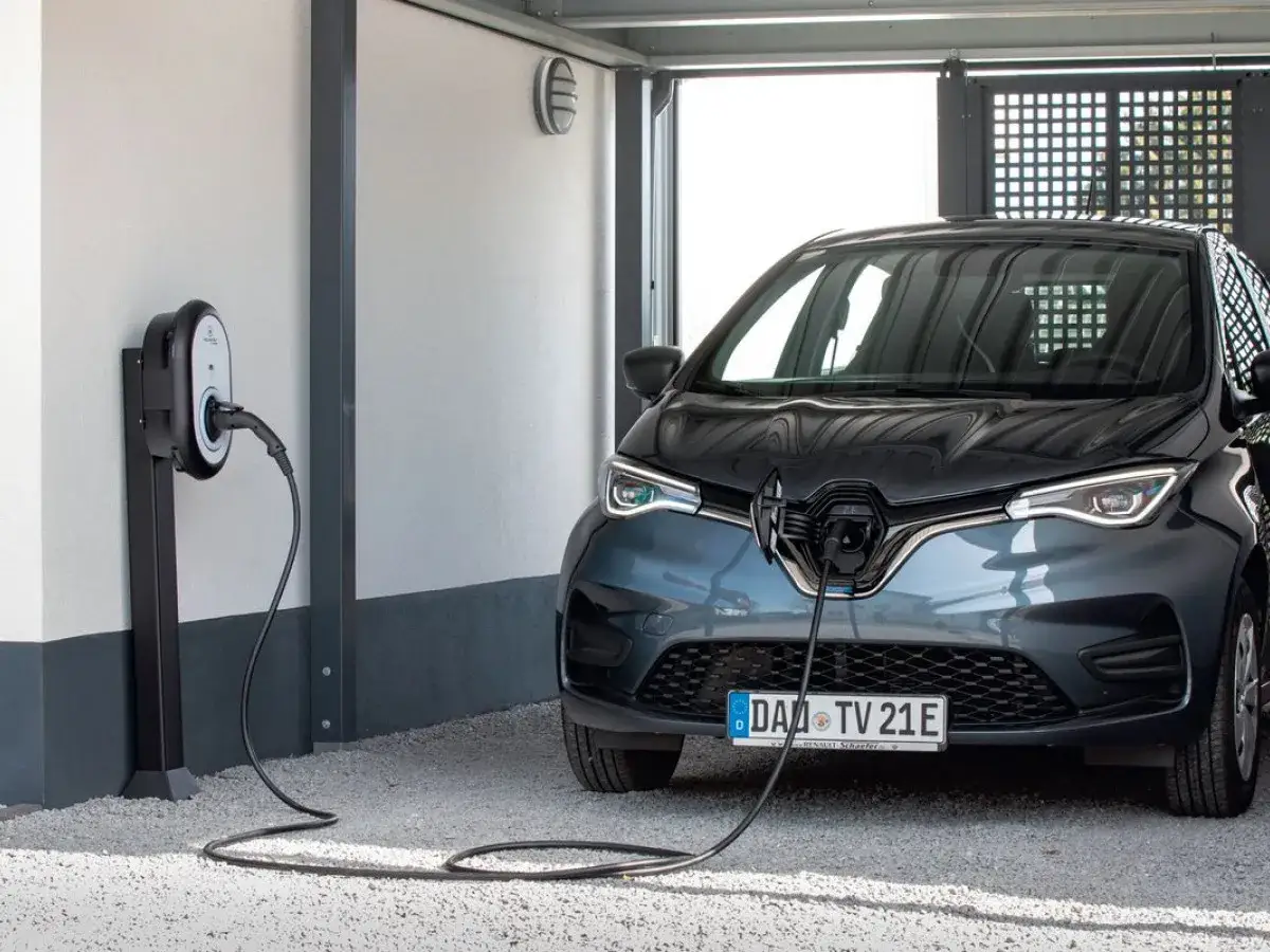 Ładowanie samochodu elektrycznego. Jaki prąd do ładowania? Stacja ładowania podłączona do ciemnoszarego Renault Zoe.