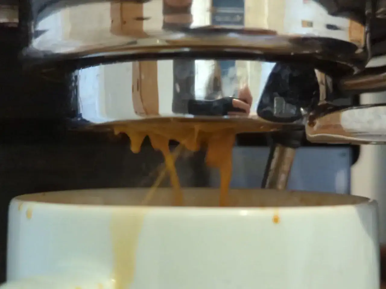 Caffè che cola velocemente dalla macchina, creando fili sottili che cadono nella tazza.