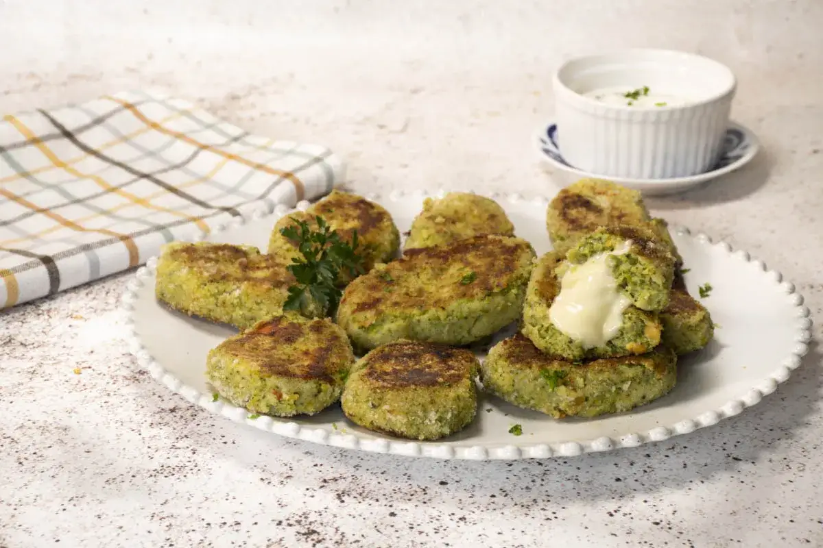 Deliciosas tortitas de br&oacute;coli, perfectas para tus recetas con br&oacute;coli. Una de ellas revela un interior cremoso de queso.