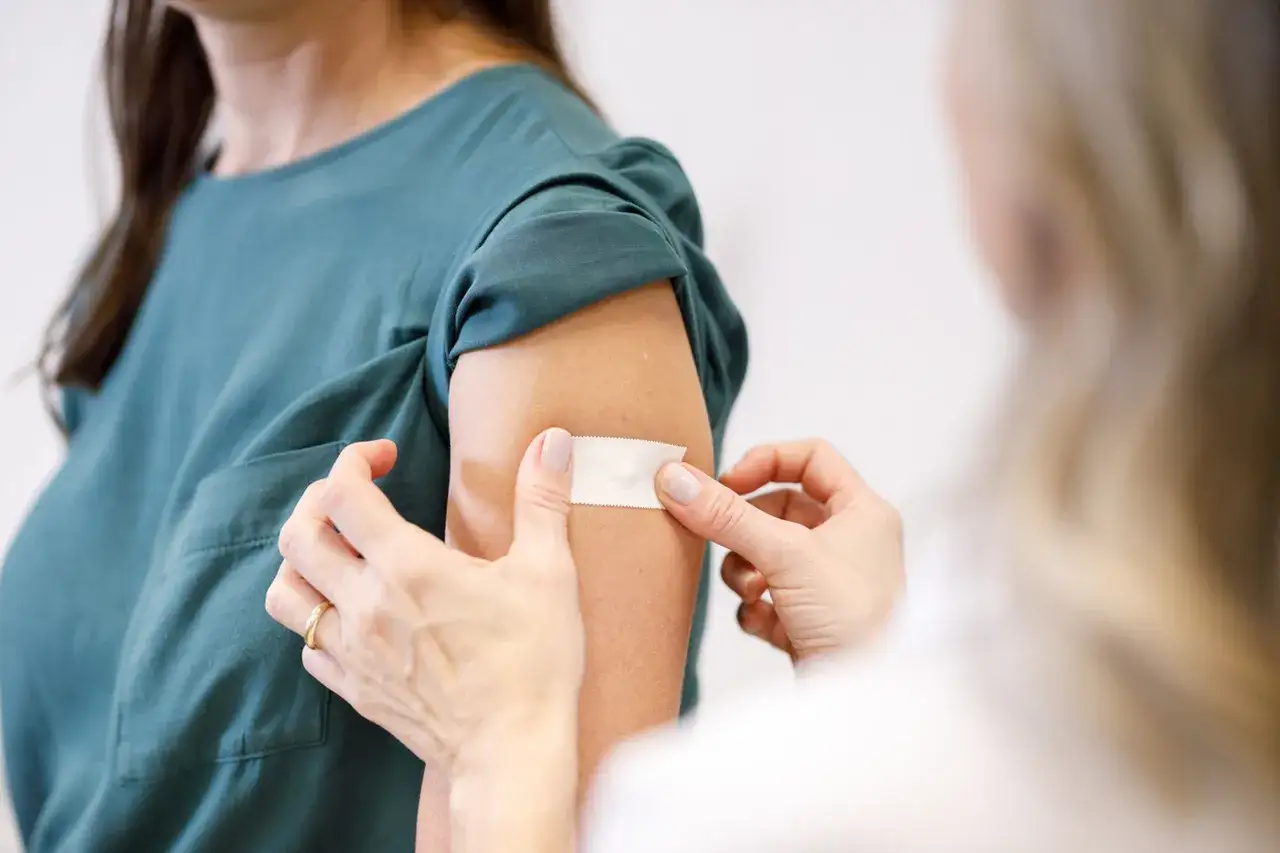 En person får ett plåster på armen efter att ha fått vaccinera influensa.