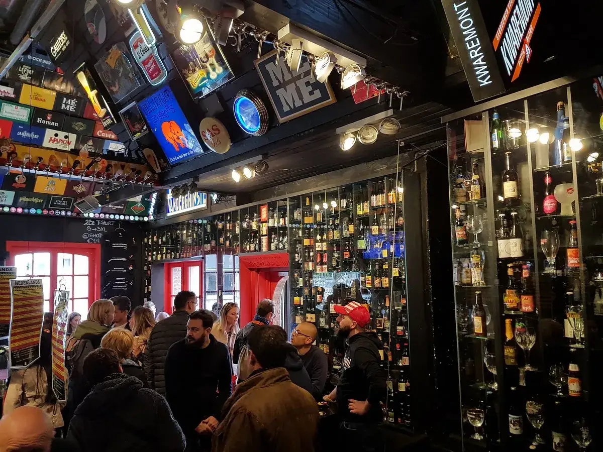 Un locale pieno di bottiglie di birra, con insegne luminose e un'atmosfera vivace. La gente &egrave; riunita, forse per una degustazione o un momento di relax, in questo paradiso per gli amanti della birra, un vero 