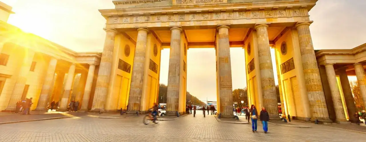 Brandenburger Tor i Berlin badar i solljus. En perfekt vy för din berlin reseguide, med människor som promenerar och cyklar.