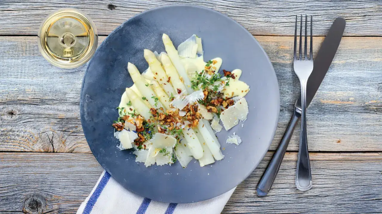 Asperges blanches napp&eacute;es d'une onctueuse sauce mousseline, garnies de noix croquantes et de copeaux de parmesan. Un d&eacute;lice printanier.