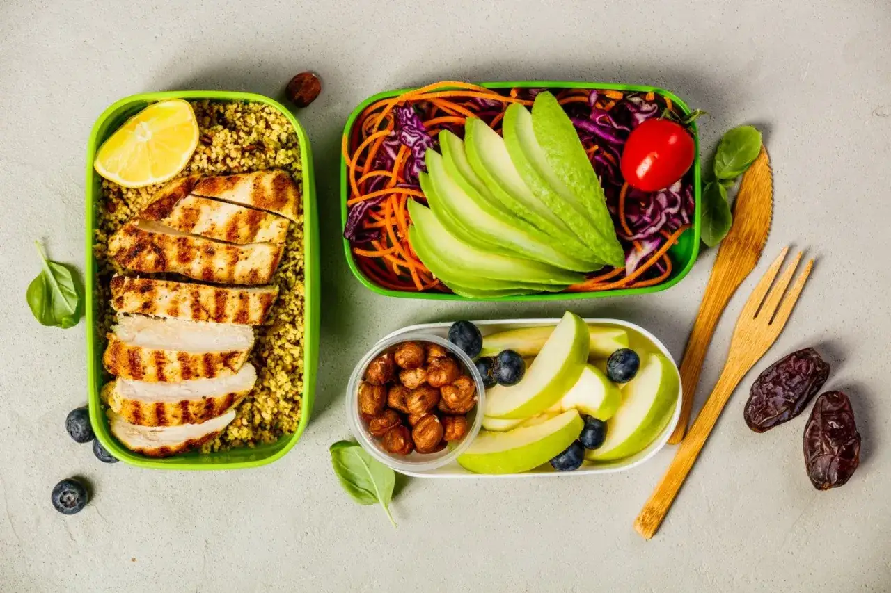 Pyszne posiłki na wynos, idealne na dietę ketogeniczną: grillowany kurczak z kaszą, sałatka z awokado i warzywami, jabłka z borówkami i orzechami.