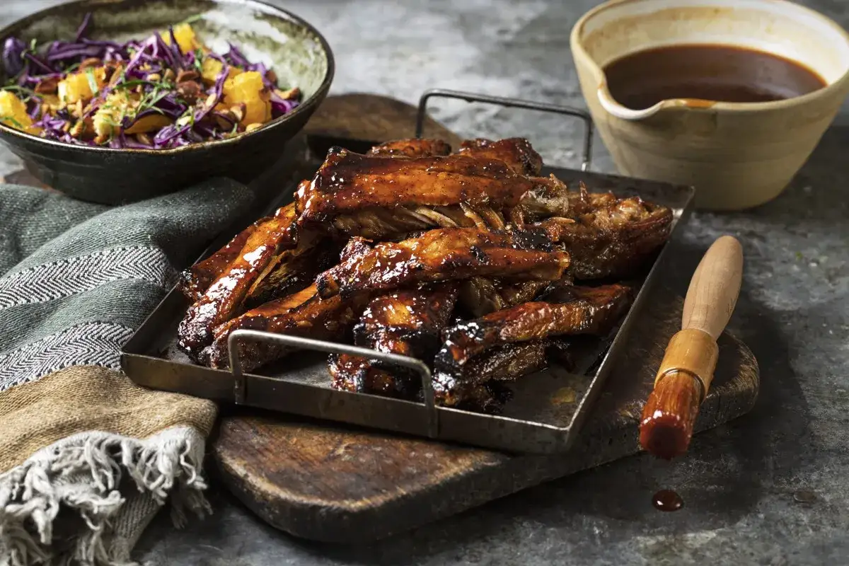 Glacerade spareribs i ugn, serverade med en fräsch kålsallad och en skål med sås. Perfekt för en härlig middag.