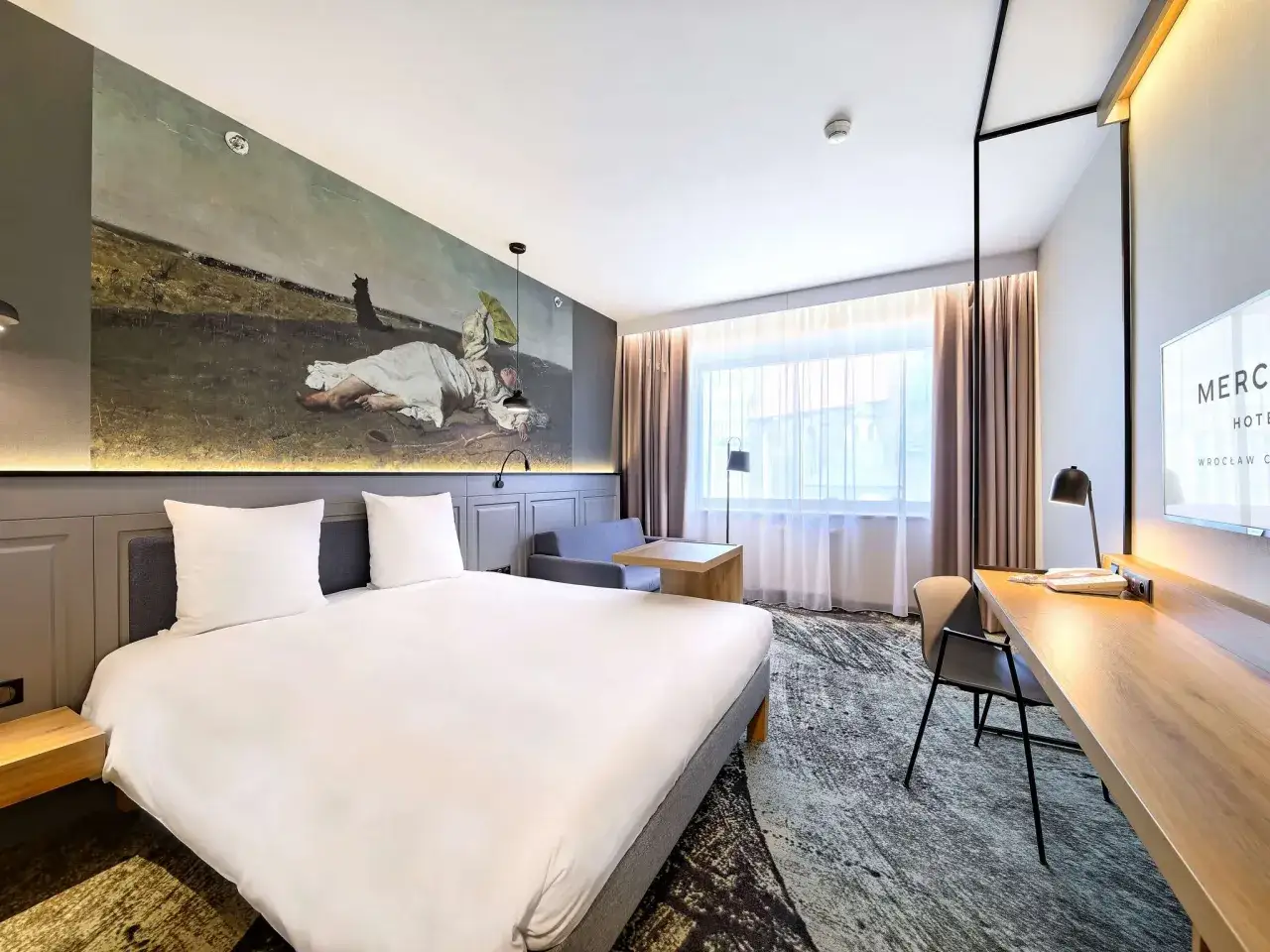 Przytulny pokój w hotelu Mercure Wrocław Centrum z dużym łóżkiem, malowidłem na ścianie i miejscem do pracy.