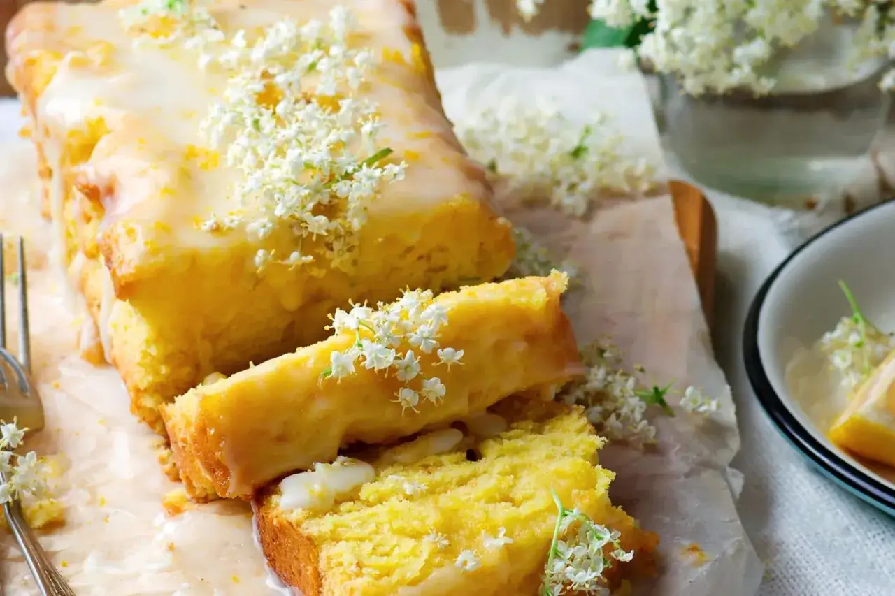 Saftiger veganer Zitronenkuchen mit Zuckerguss und Holunderbl&uuml;ten verziert. Ein Genuss f&uuml;r Augen und Gaumen.